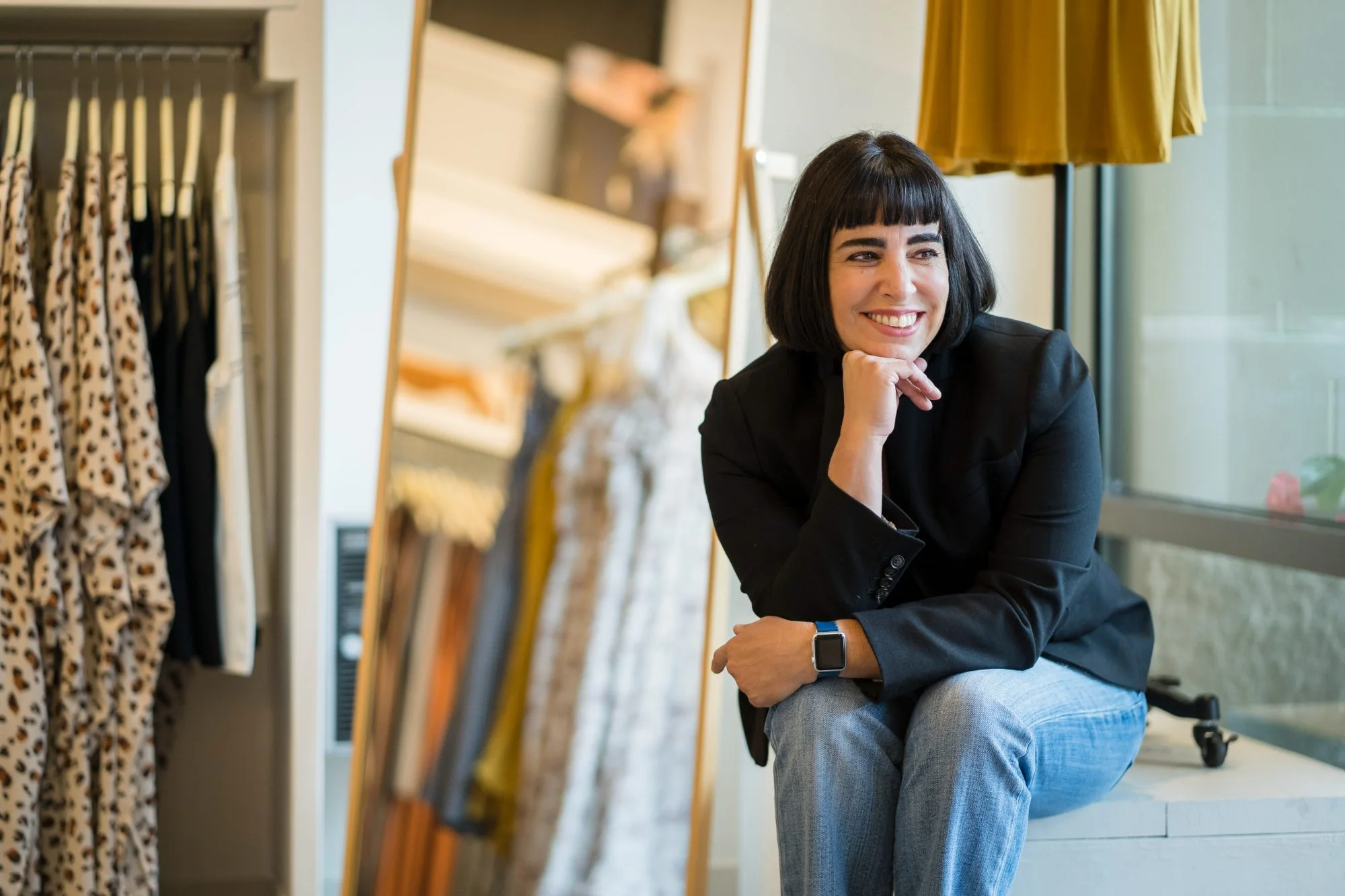 Rachel Williamson seated inside a boutique, hands clasped, looking at the camera